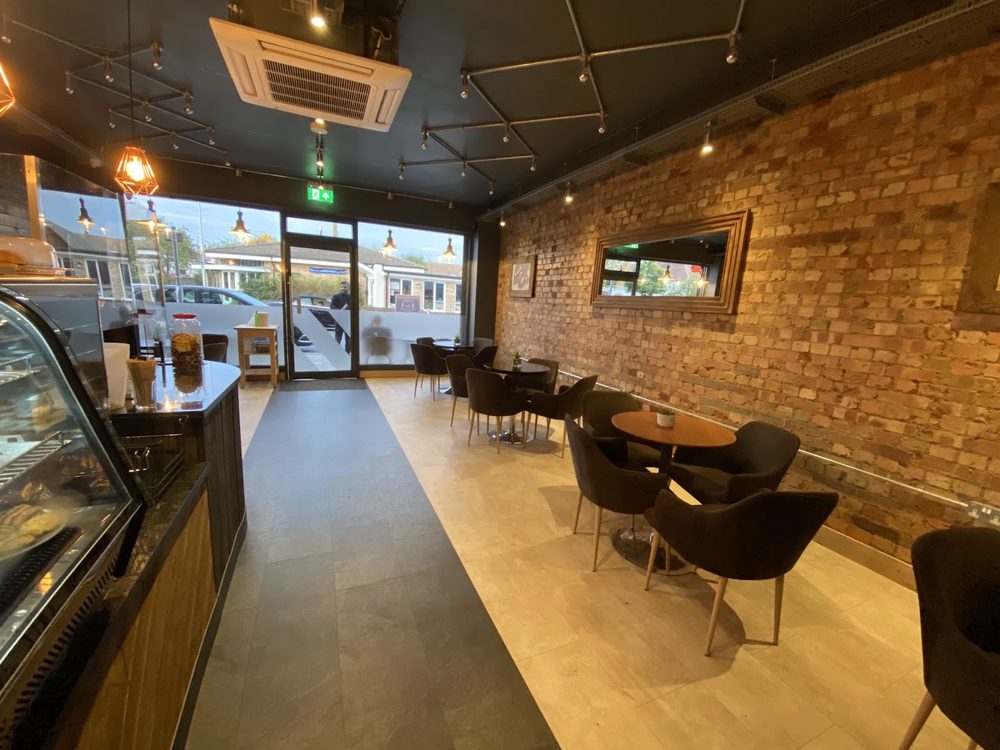 Looking from the counter down the room towards the front windows, past the brick wall and empty tables