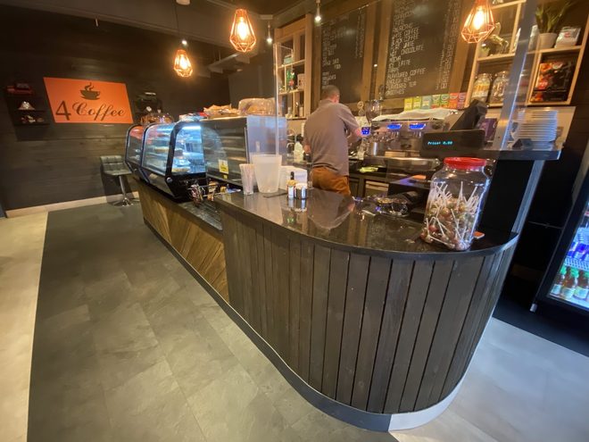 The dark curved service counter with the espresso station behind it