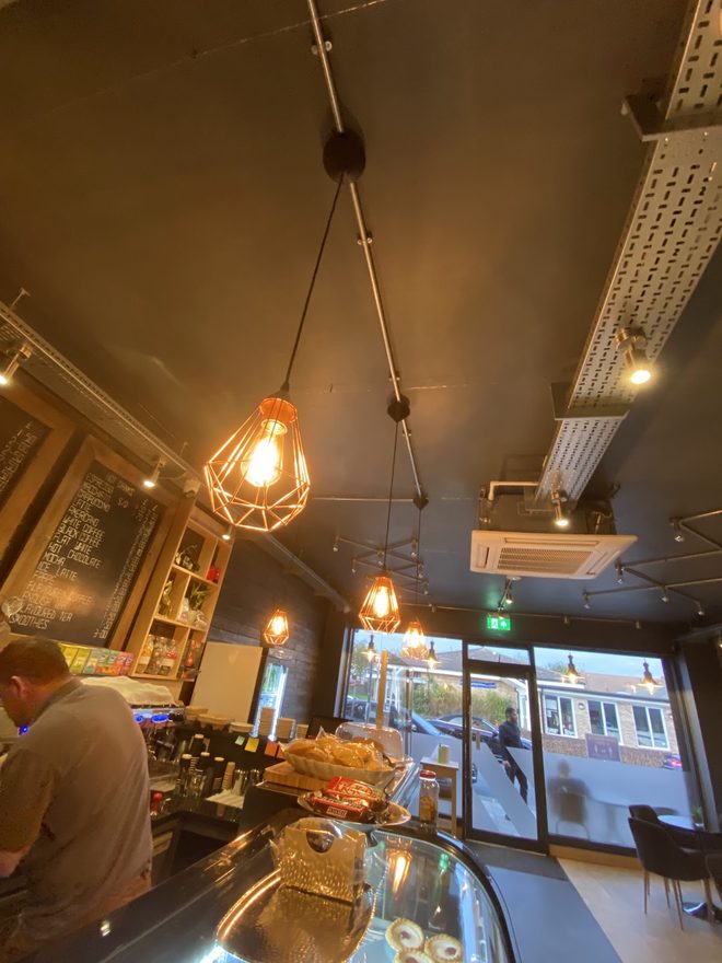 Looking along the counter towards the front windows under cage pendant lights