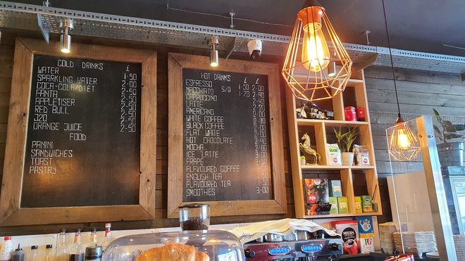 Timber wall above the counter with retail shelving and pendant lights