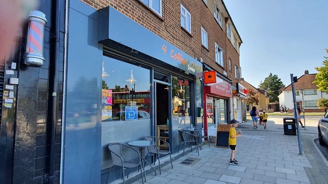 The parade of shops on Moray Way with the cafe's outside tables in evening light