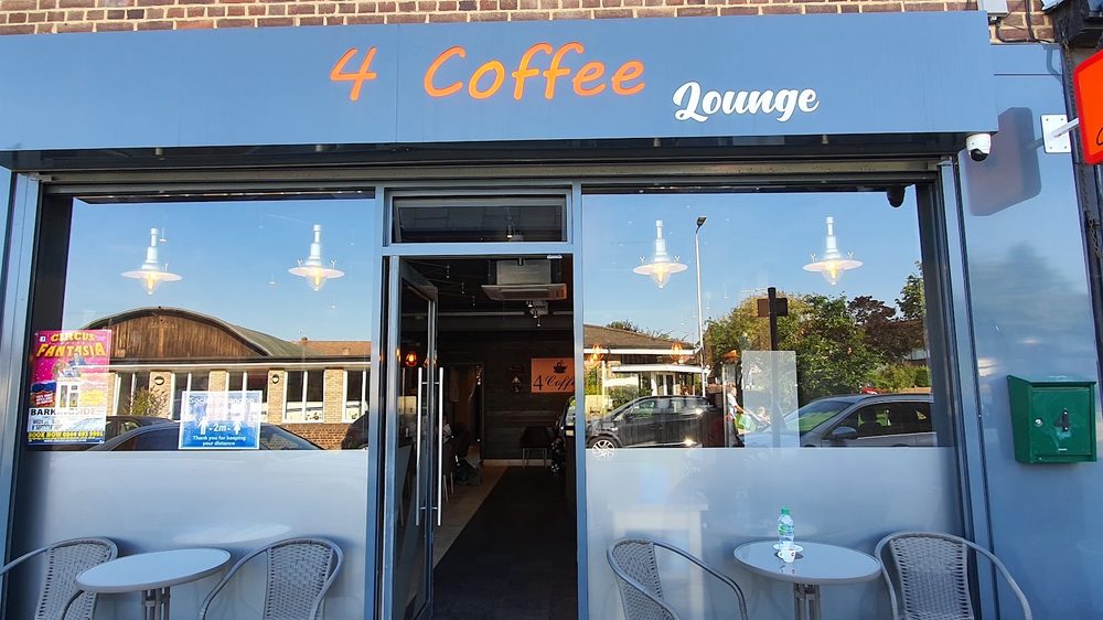 The open glass doors and sign above the entrance to 4 Coffee Lounge, seen from the pavement on Moray Way